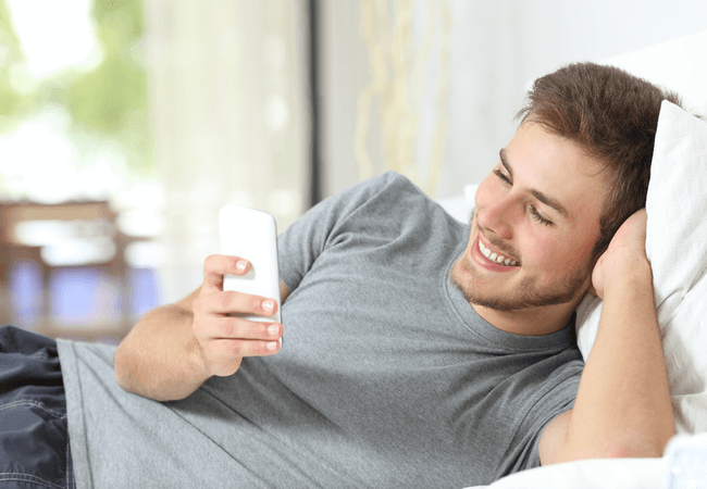 a man lying on a bed texting