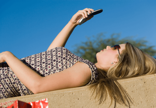 a woman laying on her back looking at her cell phone for a contact